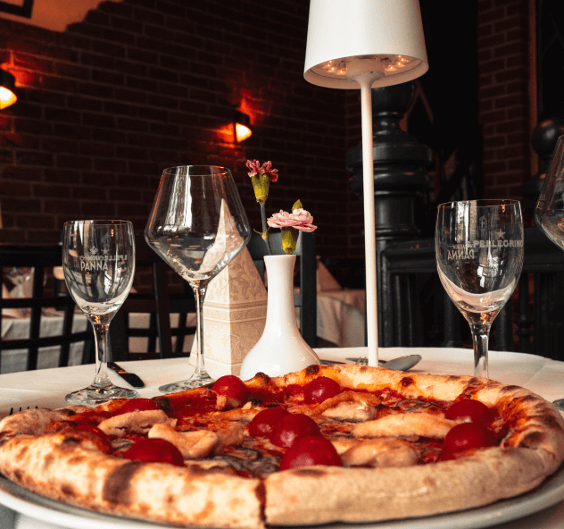 Hausgemachte Pizza aus dem Steinofen in Leipzig Gedeckter Tisch mit Weingläsern und einer Pizza